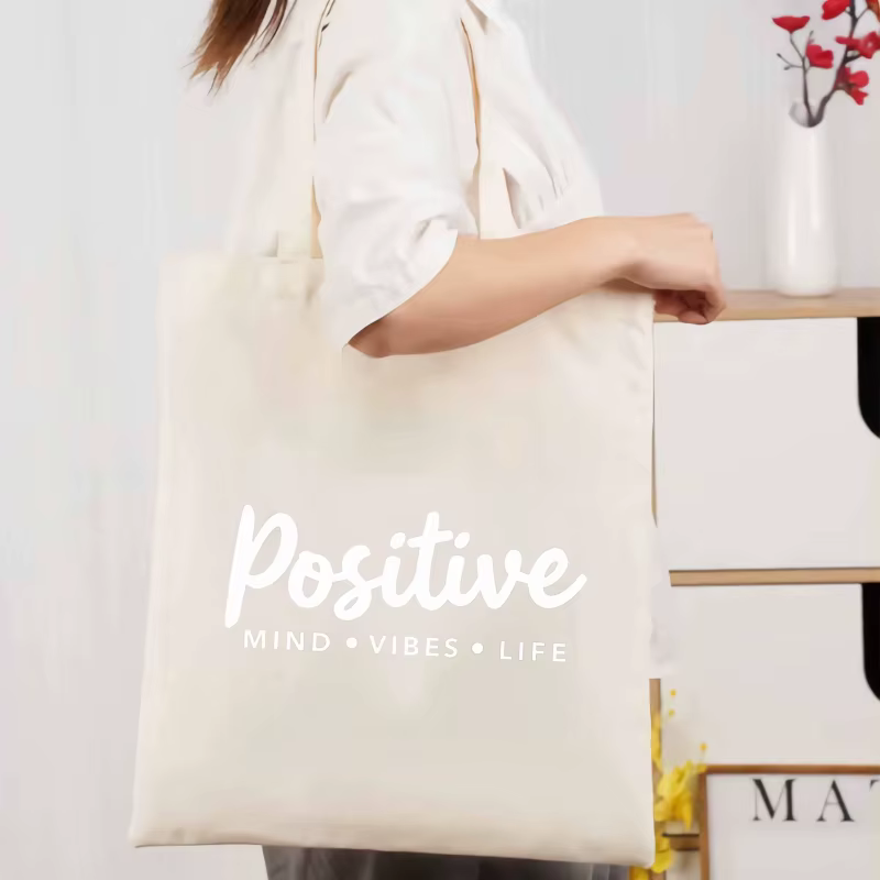 Sac fourre-tout en toile de couleur crème avec slogan vivant mindset positif imprimé sur le devant, 